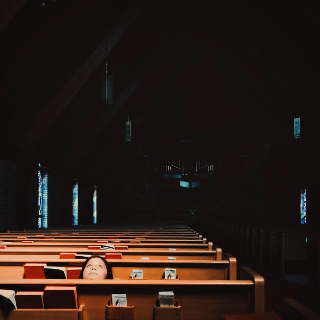 Menina olhando para cima enquanto está sentada em um banco na igreja