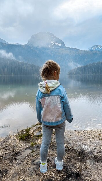 Menina olhando para o belo lago com montanhas ao fundo