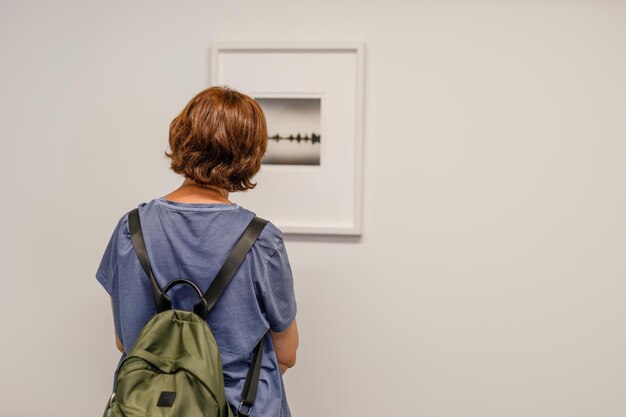 Foto menina olhando para uma pequena pintura em um museu