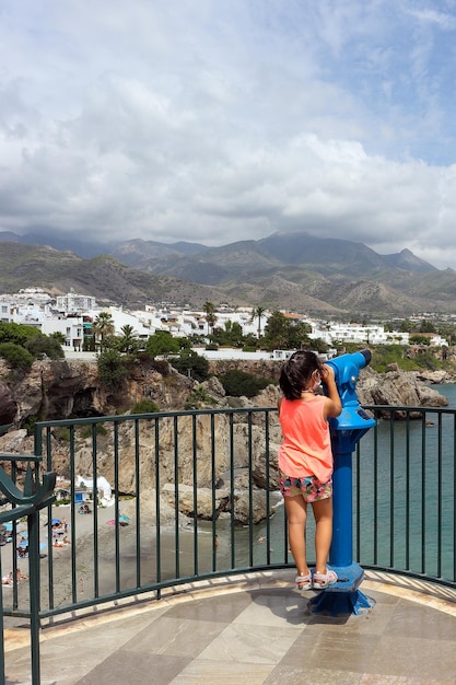 Foto menina olhando pelo telescópio para as vistas do balcon de europa em nerja