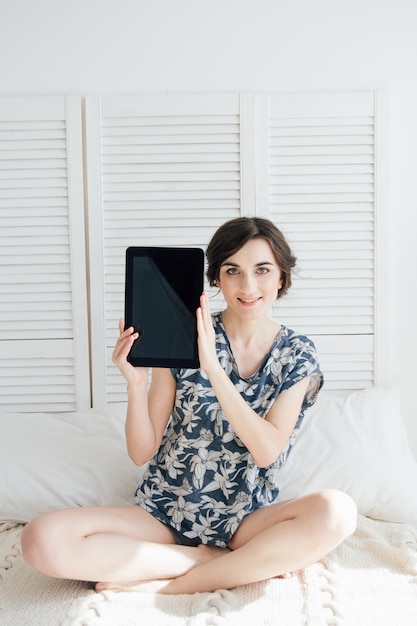 Menina olhando tablet na cama