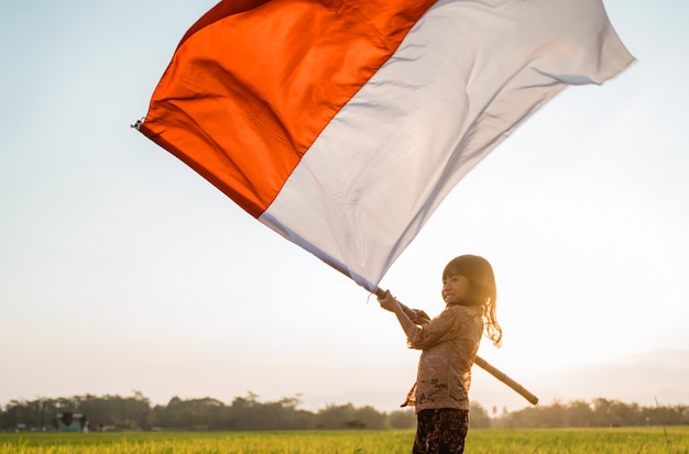 Menina orgulho agitando bandeira indonésia com felicidade