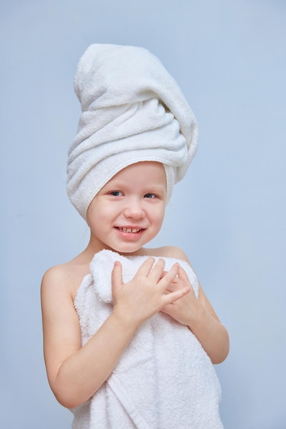 Foto menina ou filha em toalhas relaxa e descansa em um salão de spa em um fundo liso