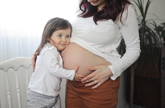 Menina ouve a barriga da mãe grávida