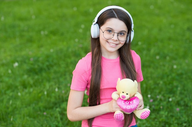 Foto menina ouvindo melodia de verão fones de ouvido sem fio natureza fundo conceito de infância feliz