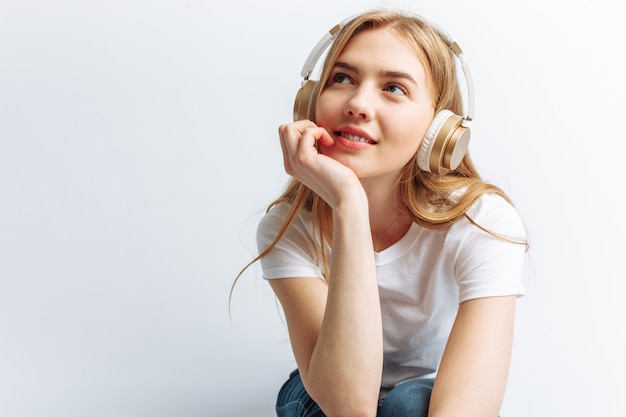 Menina ouvindo música através de fones de ouvido grandes e sentado no laptop