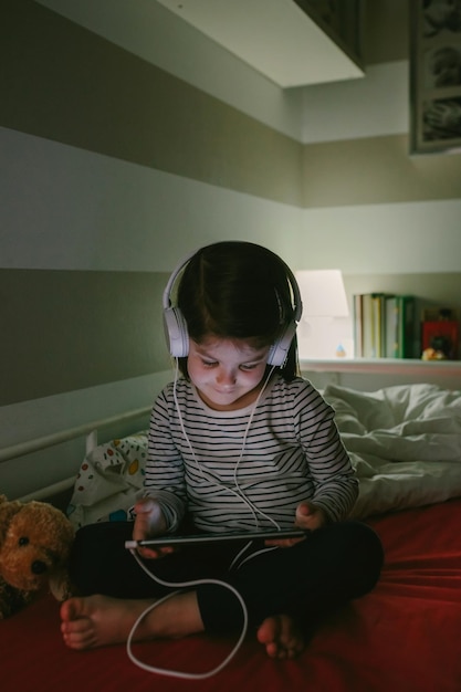 Foto menina ouvindo música enquanto usa tablet digital em casa