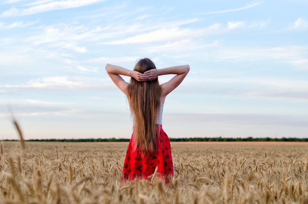 Menina parada em um campo de trigo