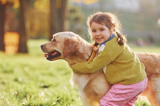 Menina passear com cachorro Golden Retriever no parque durante o dia