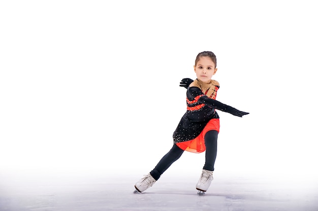 Menina patinadora em um lindo vestido preto e vermelho patinando em uma arena de gelo coberta