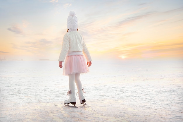 Menina patinando no gelo à luz do sol ao anoitecer
