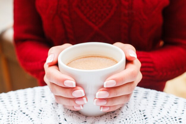 Menina pendurado café quente na xícara