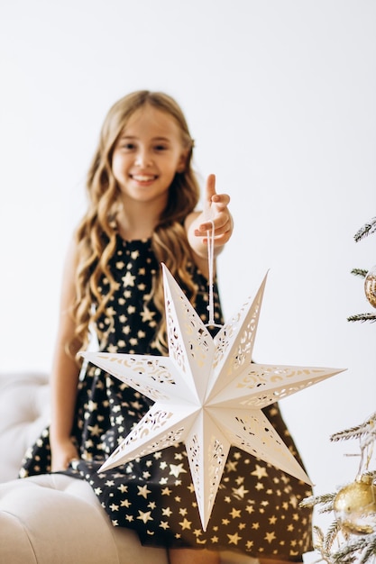 Menina pendurando brinquedos de Natal na árvore de Natal