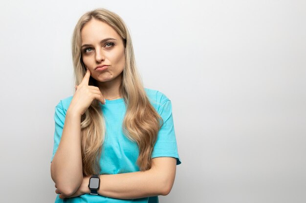 Menina pensativa em uma camiseta azul sobre um fundo branco