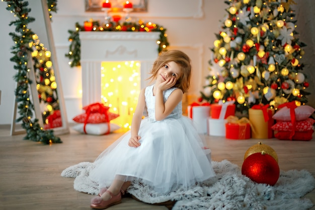 Menina pensativa, sentada na sala de Natal decorada