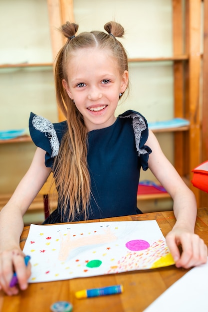 Menina pequena adorável da escola com as notas e os lápis ao ar livre.