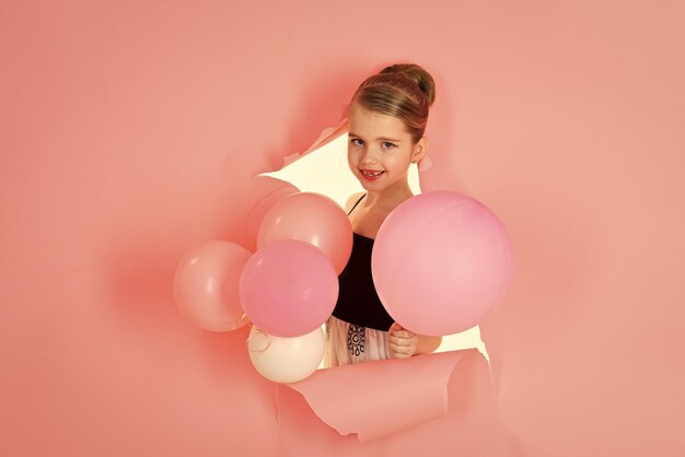 Menina pequena com balões de festa, celebração. menina em fundo rosa