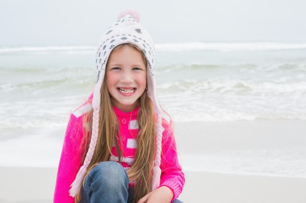 Menina pequena com roupas quentes na praia