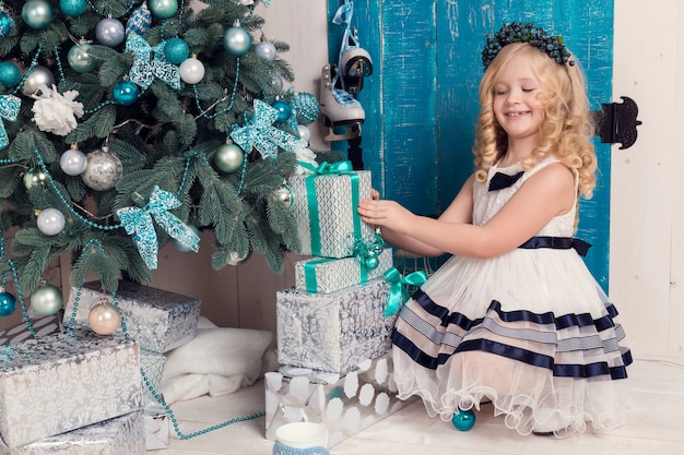 Menina pequena feliz em um vestido com seus presentes de Natal