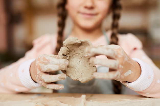 Menina pequena que dá forma à argila