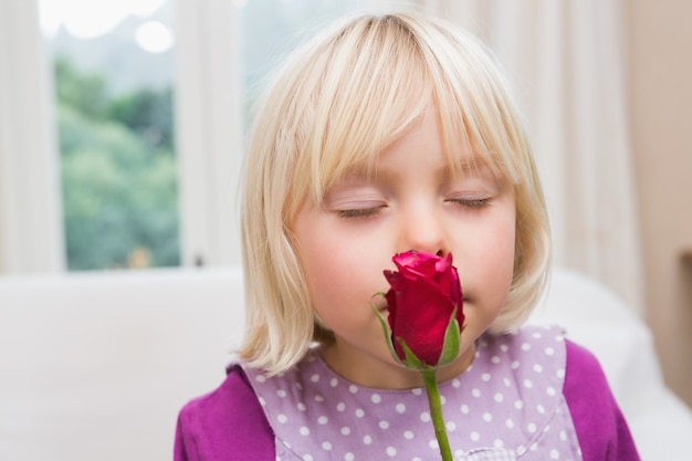 Menina pequena que prende uma rosa vermelha