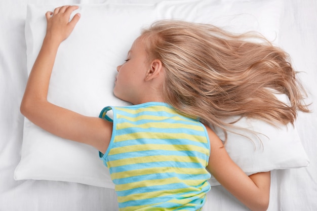 Menina pequena relaxada dormindo na cama