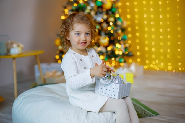 Menina perto da árvore de Natal brincando com brinquedos de Natal