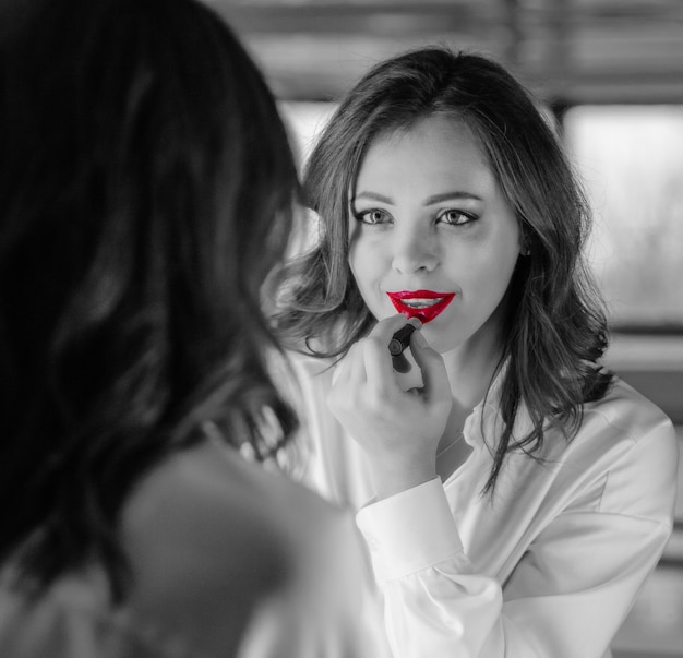 Menina pinta os lábios no espelho Preto e branco com elementos coloridos BW com lábios vermelhos