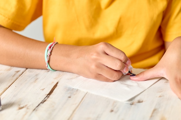 Menina pintando as unhas, nenhum rosto mostrado, conceito de manicure