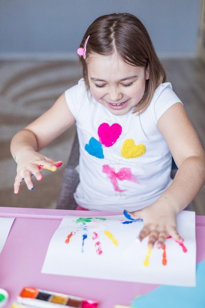 Menina pintando com as mãos e dedos em casa