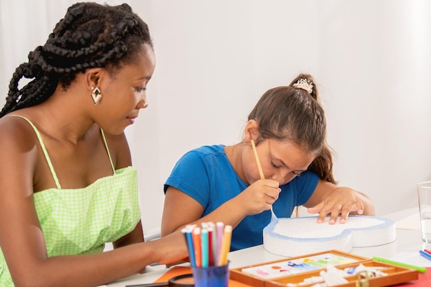 Menina pintando com seu professor na aula de arte. Pessoas multiétnicas na aula de arte.