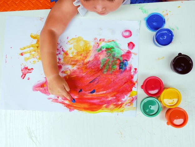 Menina pintando com tinta de dedo pintura de cor