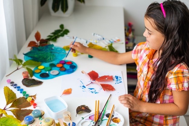 Menina pintando no outono amarelo folhas com guache, artes infantis, criatividade das crianças, arte outono.