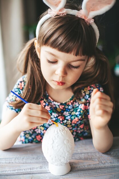 Menina pintando ovo de páscoa de gesso