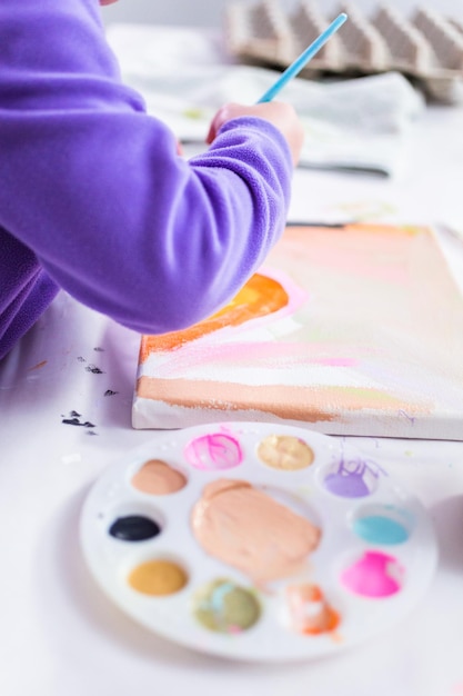 Foto menina pintando sobre tela com tinta arcílica.