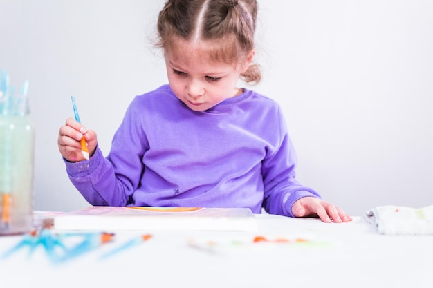 Menina pintando sobre tela com tinta arcílica.