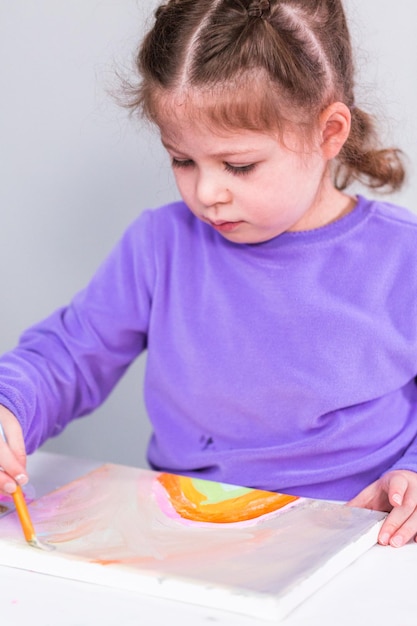 Menina pintando sobre tela com tinta arcílica.