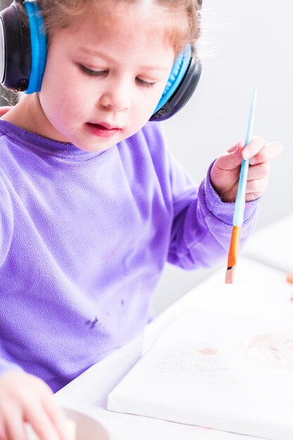 Menina pintando sobre tela com tinta arcílica.