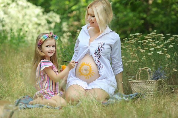Menina pintando sol na barriga da mamãe grávida