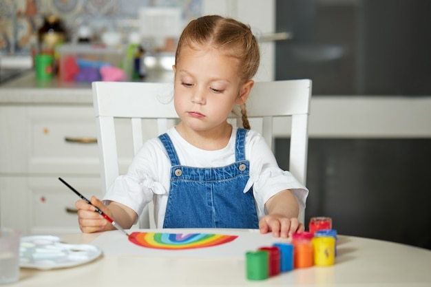 Menina pintando um arco-íris em casa