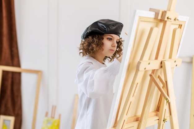 Menina pintando um quadro em um estúdio ou escola de arte criativa pintor pensativo criança pinta um col