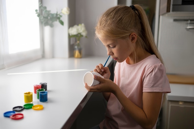 Menina pintando vaso em casa