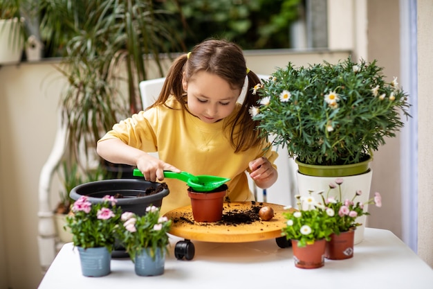 Menina plantando flores na varanda, cuidando das plantas