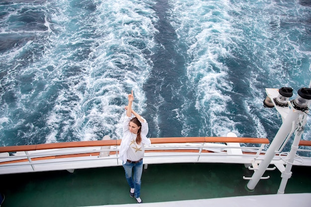 Foto menina posando na popa de um navio de cruzeiro enquanto viaja no oceano