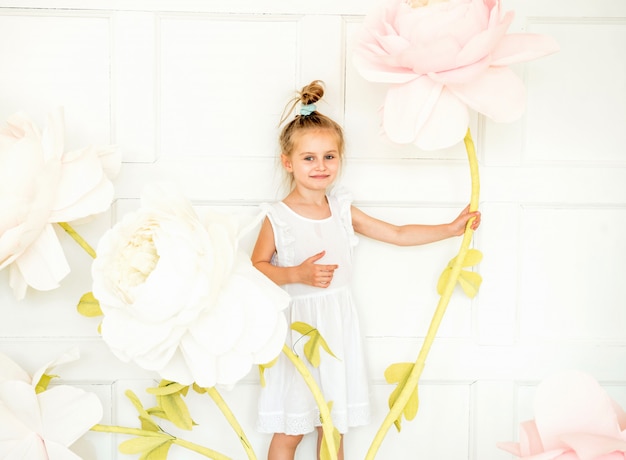 Foto menina posando no estúdio em frente a decoração com flores artificiais