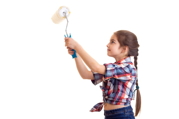 Menina positiva com longa trança castanha na camisa xadrez vermelha e jeans azul segurando rolo branco