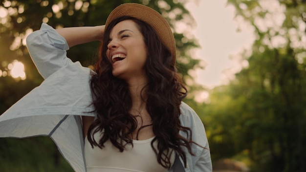 Menina positiva recebendo boas notícias no celular ao ar livre Mulher alegre pulando com emoção positiva no parque ao pôr do sol Retrato de mulher feliz virando-se durante caminhada na estrada do parque