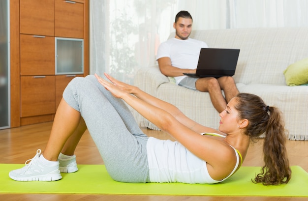 Menina praticando fitness e namorado descansando