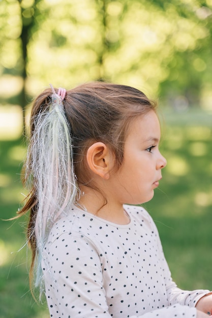 Foto menina pré-escolar com retrato de cabelo artificial com colarinho ventilador de vista lateral ao ar livre com penteado infantil da moda