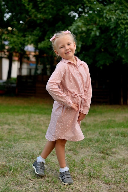 Menina pré-escolar usa um vestido rosa em bolinhas brancas no parque